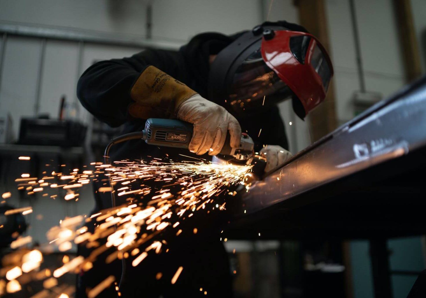 josh-beech-tXJhAFVOHVk-unsplash (1) man using angle grinder on a piece of metal